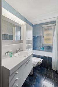 La salle de bains est pourvue d'un lavabo blanc et de carrelage bleu. dans l'établissement Cozy 2 Bedroom Apartment in Zurich, à Zurich