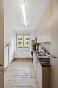 Cozy 2 Bedroom Apartment in Zurich في زيورخ: مطبخ أبيض مع حوض ونافذة