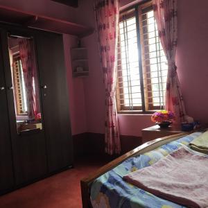 1 dormitorio con 1 cama con paredes y ventanas de color rosa en Roam Alone Roomstay near International airport, en Gurpur
