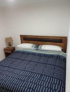 Bett mit blauer Bettdecke und Kopfteil aus Holz in der Unterkunft DEPARTAMENTO DICHATO in Tomé