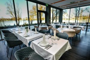 ein Restaurant mit weißen Tischen und Stühlen und Fenstern in der Unterkunft Best Western Plus Lakeside Hotel in Székesfehérvár