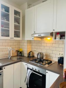 uma cozinha com armários brancos e um forno com placa de fogão em Quiet and Colorfull Flat in the Center City of Brussels em Bruxelas