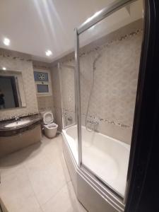 a bathroom with a shower and a tub and a toilet at شقه مفروشه مجهزه 5***** in Cairo