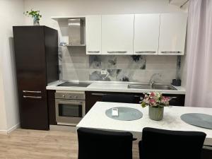 cocina con armarios blancos y nevera negra en ROYAL MILANO LINATE APARTMENTS, en Pantigliate