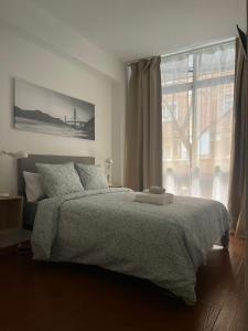 1 dormitorio con cama y ventana grande en Rooms Cáceres en Madrid