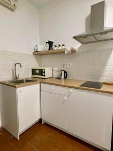 a kitchen with white cabinets and a sink at Rooms Cáceres in Madrid