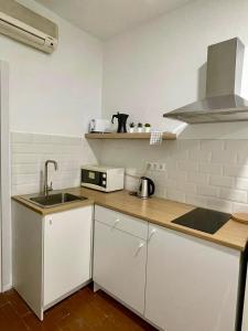 eine weiße Küche mit einer Spüle und einer Mikrowelle in der Unterkunft Rooms Cáceres in Madrid