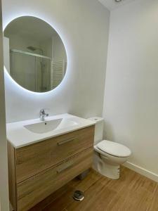 a bathroom with a sink and a toilet with a mirror at Rooms Cáceres in Madrid