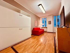 ein Wohnzimmer mit einem roten Stuhl und einem Kühlschrank in der Unterkunft Kibilù - Via Medaglie D'Oro Centro Città con Parcheggio in Varese