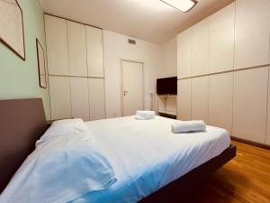 sypialnia z dużym białym łóżkiem z 2 ręcznikami w obiekcie Kibilù - Via Medaglie D'Oro Centro Città con Parcheggio w mieście Varese