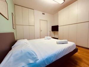 une chambre avec un grand lit blanc avec deux serviettes dessus dans l'établissement Kibilù - Via Medaglie D'Oro Centro Città con Parcheggio, à Varèse