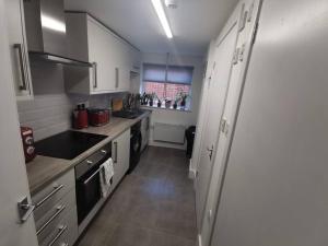 een kleine keuken met witte kasten en een raam bij Unique LFC Themed House in Liverpool +5 foto's