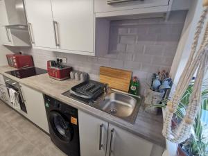 een keuken met een spoelbak en een wasmachine bij Unique LFC Themed House in Liverpool