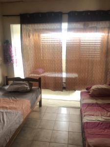 a bedroom with two beds and a window with blinds at The Green House in Bocas del Toro