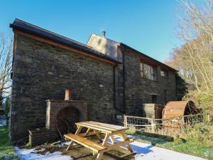 a wooden picnic table in front of a brick building at Y Felin in Llanybydder