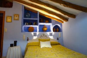 Un dormitorio con una cama amarilla y paredes azules en Casa Rural Manubles en Bijuesca