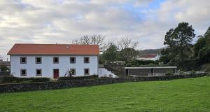 a white house with a red roof in a field at Casa de Campo Franco da Serra in Angra do Heroísmo