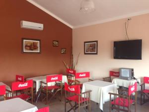 a restaurant with red chairs and tables and a flat screen tv at Hotel Valle Colorado in Villa Unión