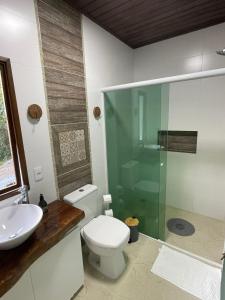 a bathroom with a toilet and a glass shower at Casa da Mata in Itapema