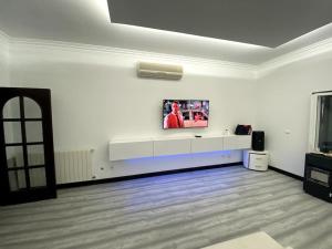 Habitación blanca con TV en la pared en Belo Jardim Villa, en Samora Correia