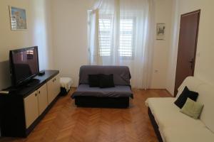 a living room with a couch and a tv at Apartments Jadrijević Brne in Primošten