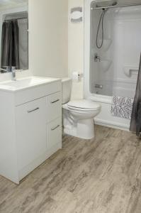 a white bathroom with a toilet and a shower at Prospectors Inn in Kirkland Lake