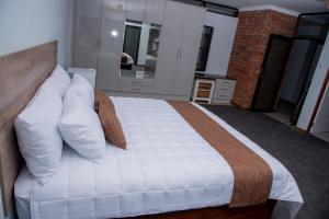um quarto com uma cama grande e almofadas brancas em Boruundi Private Lodge & Campsite em Bokaa
