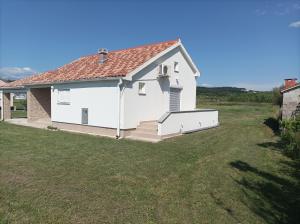 een wit huis met een gazon ervoor bij Kuća za odmor ANA in Ljubač