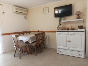 een eetkamer met een tafel en een tv aan de muur bij Kuća za odmor ANA in Ljubač