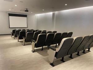 a conference room with black chairs and a white screen at Apt no Thermas São Pedro Resort in São Pedro