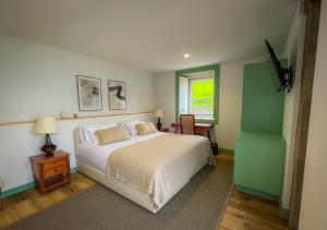 a bedroom with a white bed and a window at Casa de Campo Franco da Serra in Angra do Heroísmo