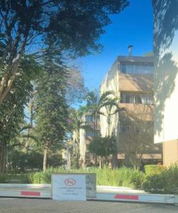 a sign in front of a building with trees at Apto aconchegante cecapGuarulhos in Guarulhos