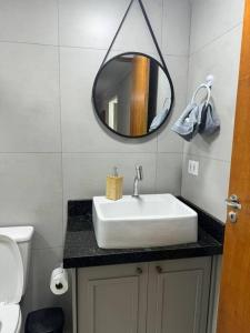 y baño con lavabo blanco y espejo. en Apto aconchegante cecapGuarulhos en Guarulhos