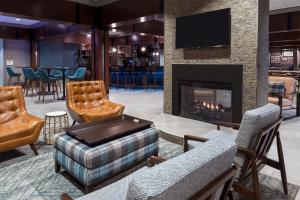 a lobby with a fireplace and chairs and a bar at Four Points Huntsville Airport in Madison