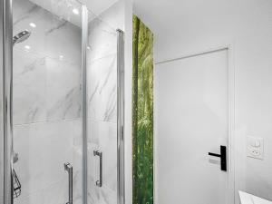 een douche met een glazen deur in de badkamer bij L'Harmonie de Livry in Livry-Gargan