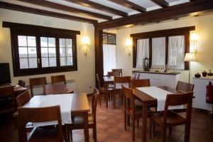 un comedor con mesas, sillas y ventanas en El Valle Hotel Rural, en Sotillo del Rincón