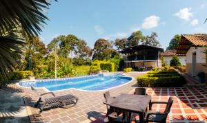 einen Pool mit einem Tisch und Stühlen neben einem Haus in der Unterkunft Hotel Campestre Nogal de Cafetal in Quimbaya