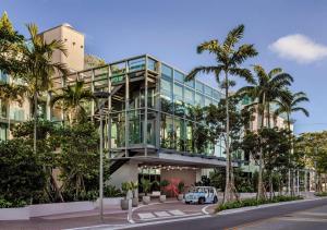 a building with a glass facade with palm trees at The Ray Hotel Delray Beach, Curio Collection By Hilton in Delray Beach