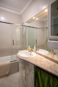 ein weißes Badezimmer mit Waschbecken und Spiegel in der Unterkunft Apartamento acolhedor em Lagos in Lagos