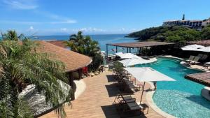 um resort com uma piscina com guarda-sóis e o oceano em HOTEL VILLE LA PLAGE & BEACH CLUB em Búzios