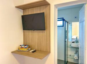 a flat screen tv on a wall in a bathroom at Incrivel flat a beira mar na Praia de Guaratuba SP in Praia Guaratuba