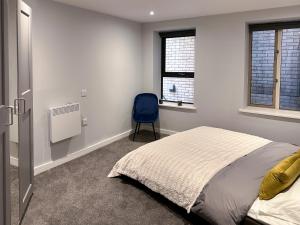 a bedroom with a bed and a blue chair at Toothbrush Apartments - Town Centre - Century House in Ipswich