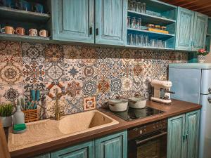 a kitchen with blue cabinets and a sink and tiles at Кътче in Leshten