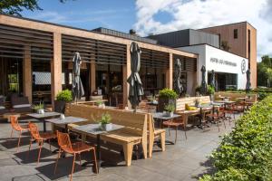 un patio extérieur avec des tables, des chaises et des parasols dans l'établissement Hotel de Sterrenberg - Adults Only, à Otterlo