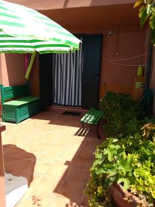 a patio with a green umbrella and a bench at MAREVIGLIOSO Fronte Mare Sea Front in Magomadas +44 photos