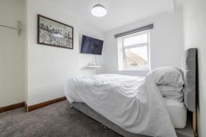 a white bedroom with a bed and a window at Countryside Getaway in Clayton West
