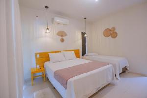 a white bedroom with a large bed and a table at Aruana Suites Tranquilidade e Sossego no meio da Natureza a 5km da Vila de Praia do forte in Praia do Forte
