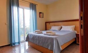 ein Schlafzimmer mit einem Bett und einem großen Fenster in der Unterkunft Arisvi All Seasons Hotel in Skala Kallonis