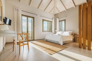 a bedroom with a bed and a table and a desk at Callisto Seaside Homes & Suites in Marathopolis