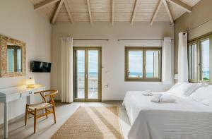 a bedroom with two beds and a desk and windows at Callisto Seaside Homes & Suites in Marathopoli